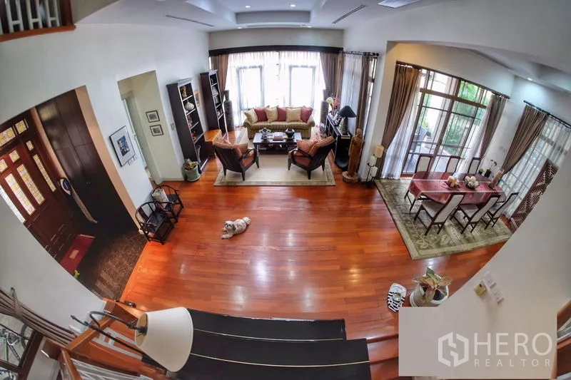 Detached House for rent in Watthana, Bangkok - View from the staircase over the open living and dining area with wide windows and wood floors.