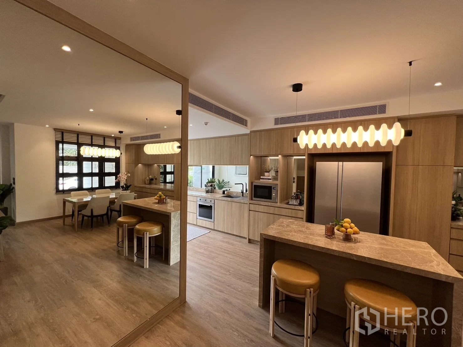 Townhouse for sale in Watthana, Bangkok - Sleek kitchen and dining with wood cabinets, large windows and pendant lights.