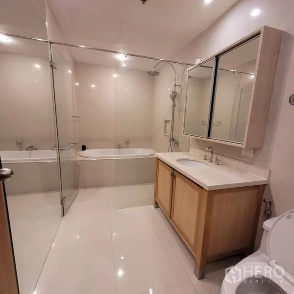 Condominium for rent in Khlong Toei, Bangkok - Modern bathroom with glass-enclosed shower, bathtub, and vanity.