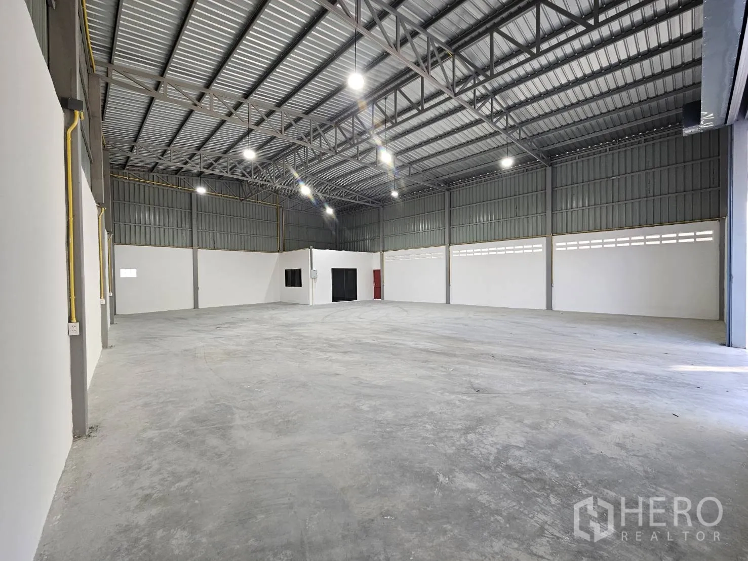 Warehouse for rent in Mueang Samut Prakan, Samut Prakan - Spacious warehouse interior with high steel truss roof and a built-in office room.