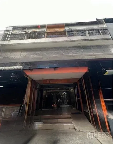 店屋 出租或出售在Watthana, Bangkok - 多层店屋的街道立面，入口内凹并带有金属栏杆阳台。