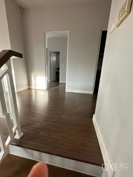 Detached House for rent or sale in Lam Luk Ka, Pathum Thani - Hallway with wood flooring and white trim leading to bedrooms.