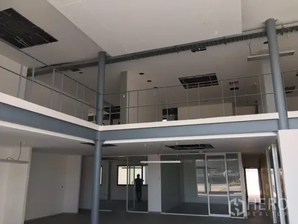 Warehouse for rent in Saphan Sung, Bangkok - Double-height office interior with mezzanine, glass partitions and exposed ceilings.