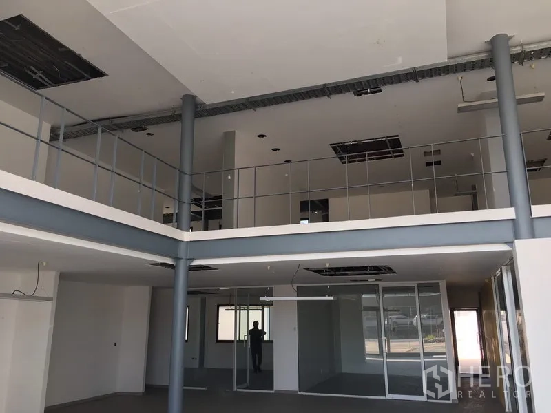 Warehouse for rent in Saphan Sung, Bangkok - Double-height office interior with mezzanine, glass partitions and exposed ceilings.