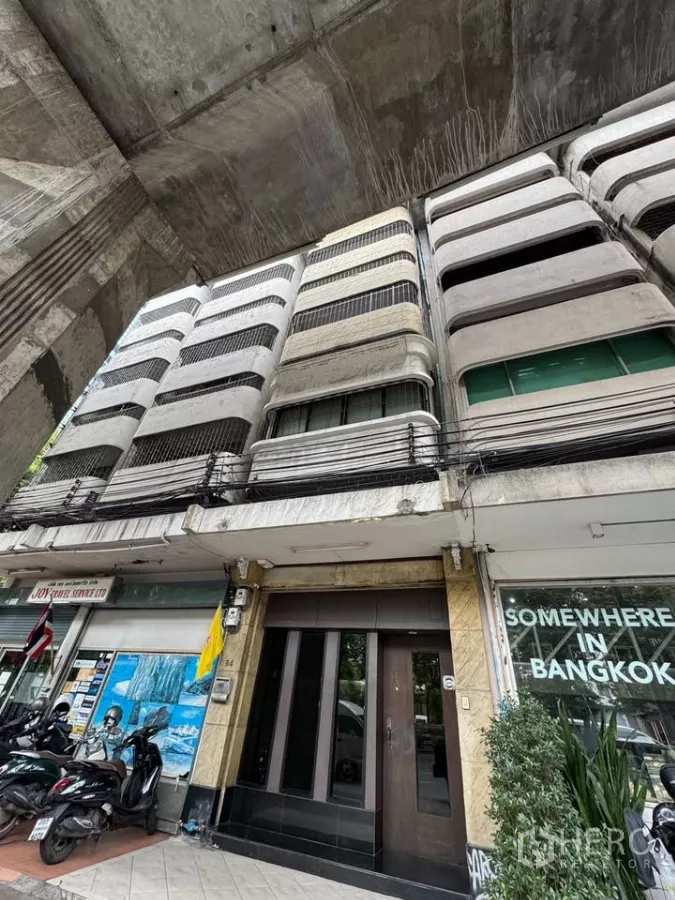 Shophouse for rent in Bang Rak, Bangkok - Street-level facade of a multi-storey shophouse beneath an elevated structure.