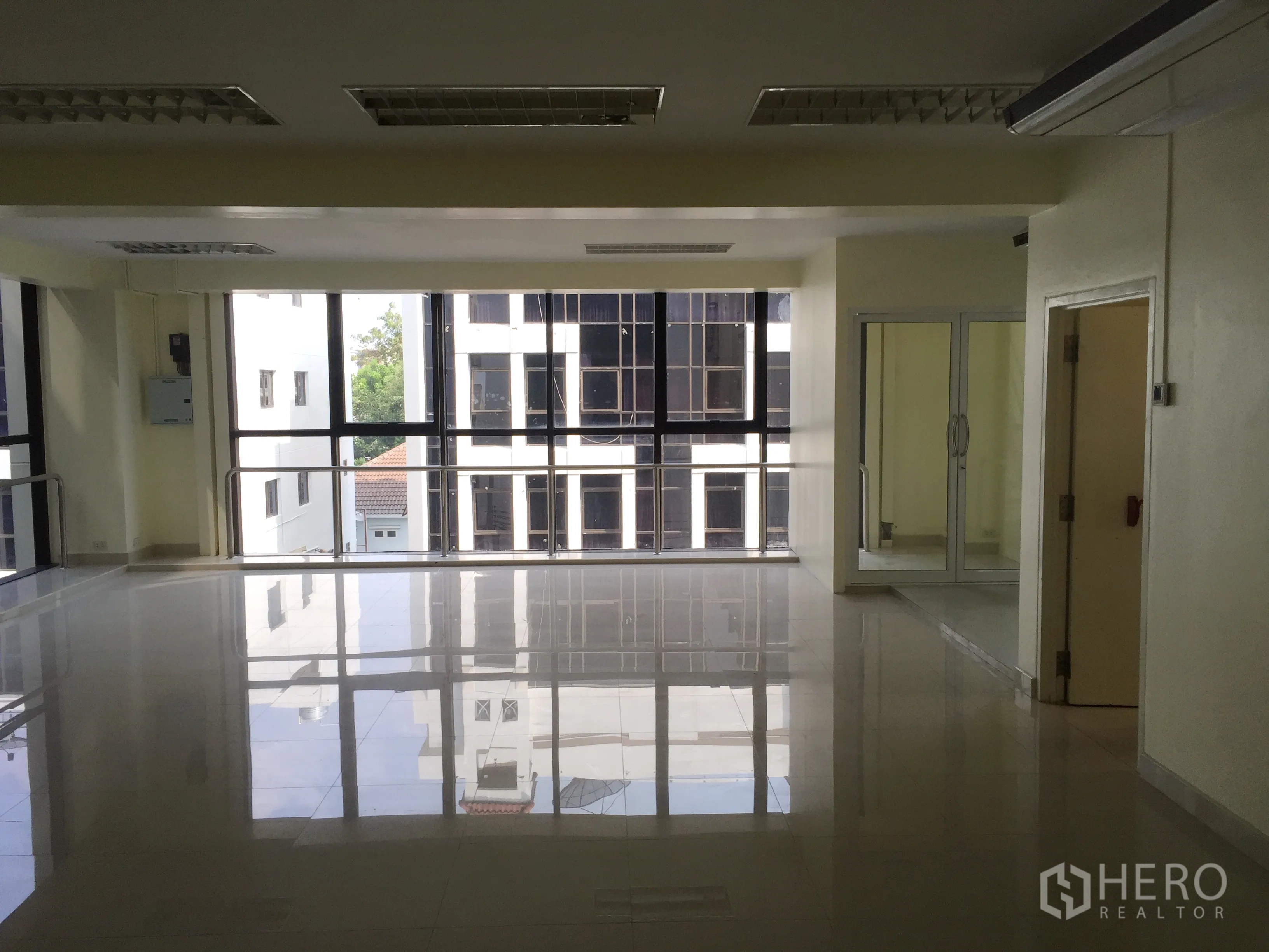 Office Space for rent in Bang Kapi, Bangkok - Open workspace with panoramic windows overlooking nearby buildings and polished tiles.