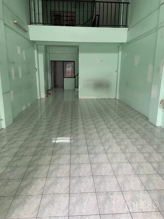 Shophouse for rent in Suan Luang, Bangkok - Ground-floor hall with glossy grey tiles leading to a mezzanine staircase.