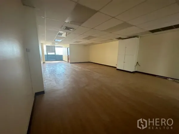 办公空间 出租 - 狭长开放工作区，天花板板块、浅色墙面与采光充足的高窗。