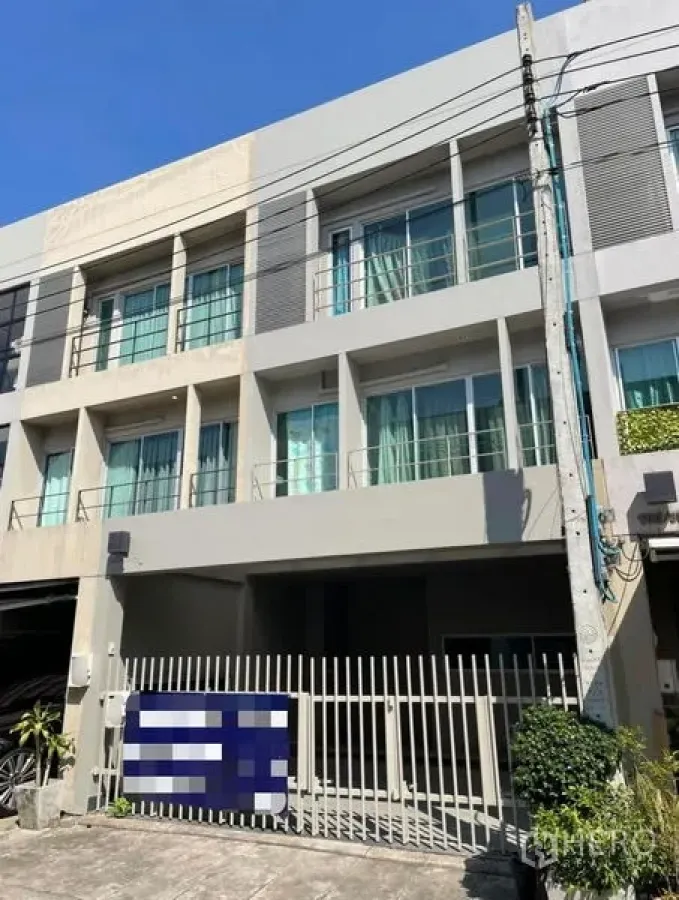 Townhouse for rent in Suan Luang, Bangkok - Three-storey modern townhouse facade with balconies, large windows and gated parking.