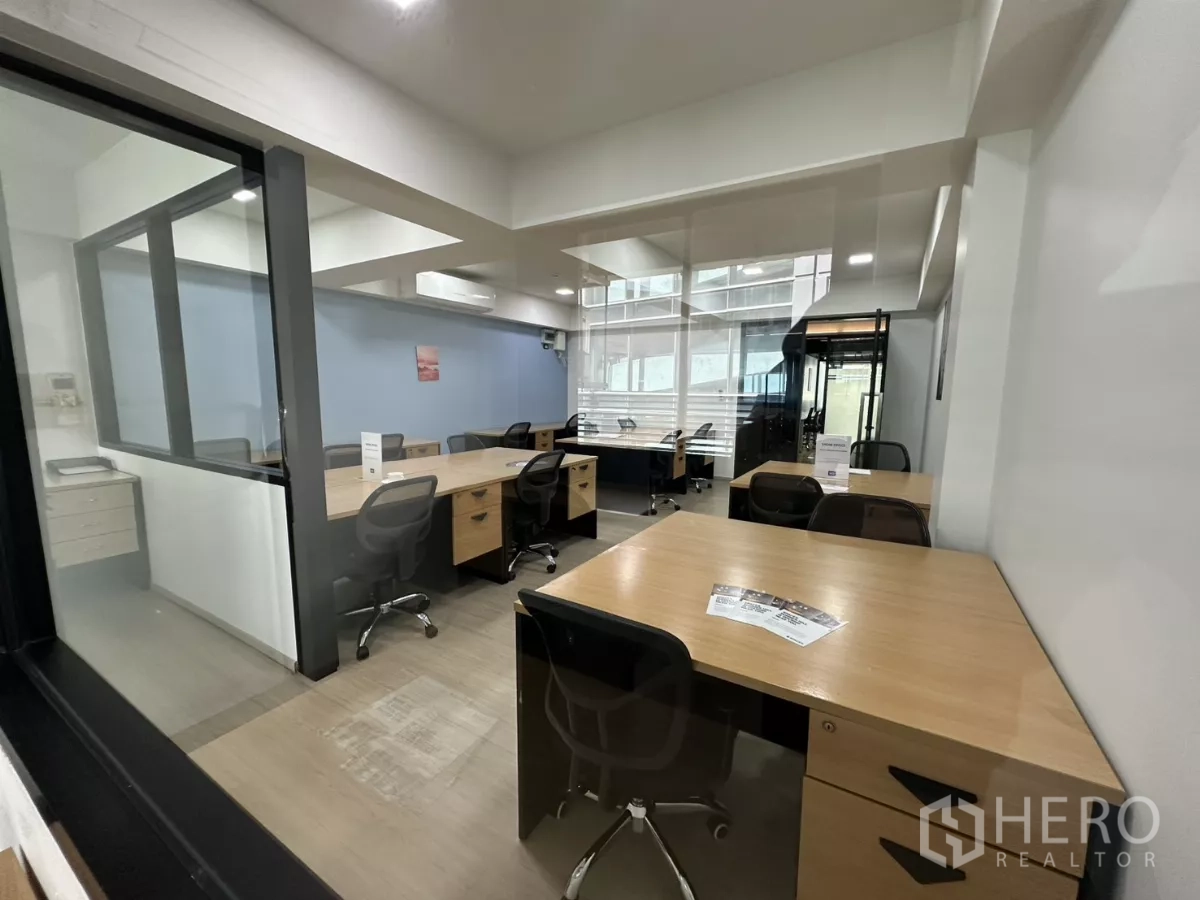 Office Space for rent in Watthana, Bangkok - View from a private room into the shared office showing desks, chairs and natural light.
