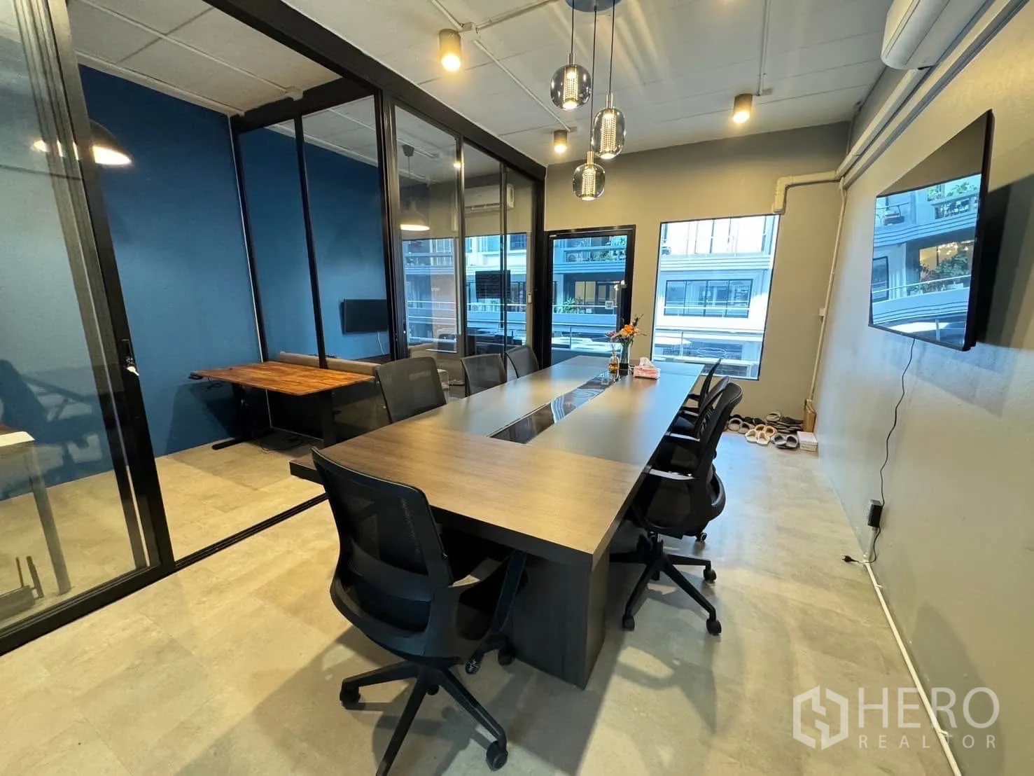 Home Office for rent in Watthana, Bangkok - Glass-partitioned meeting room with a long conference table, pendant lights and TV.