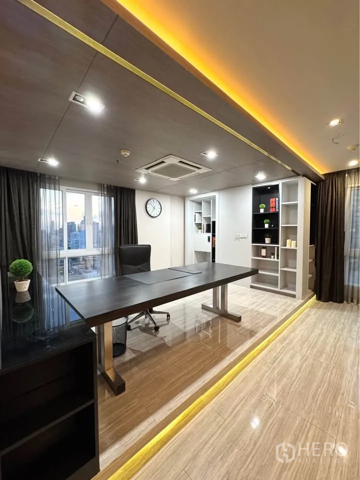 Condominium for rent or sale in Khlong Toei, Bangkok - Home office corner with large desk, built-in shelving and a city view window.