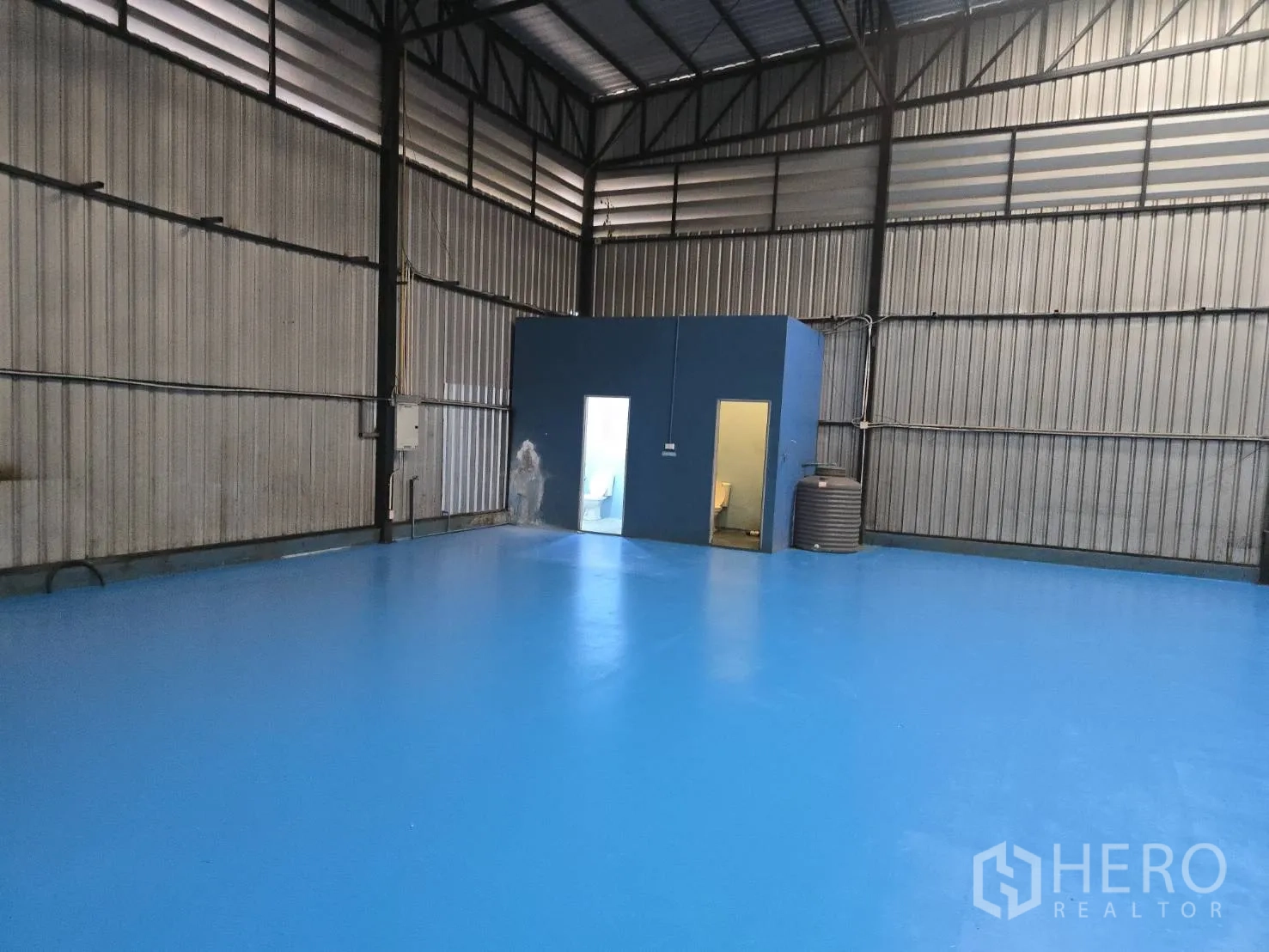 Warehouse for rent in Bang Phli, Samut Prakan - View across the warehouse toward a utility room and water tank.