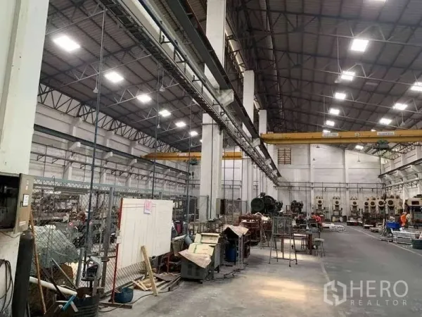 Factory for rent in Phra Samut Chedi, Samut Prakan - Production aisle under bright LED lighting with columns and twin overhead cranes.