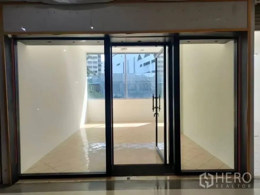 Retail Space for rent - Bright compact retail unit with recessed ceiling lights and clear glass entrance, viewed from a mall corridor in Bangkok.