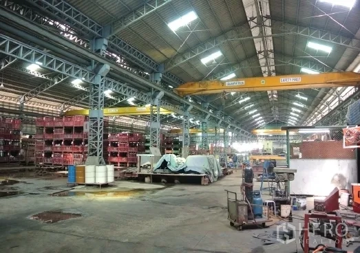 Factory for sale in Bang Phli, Samut Prakan - Workshop aisle with storage racks and yellow gantry cranes.