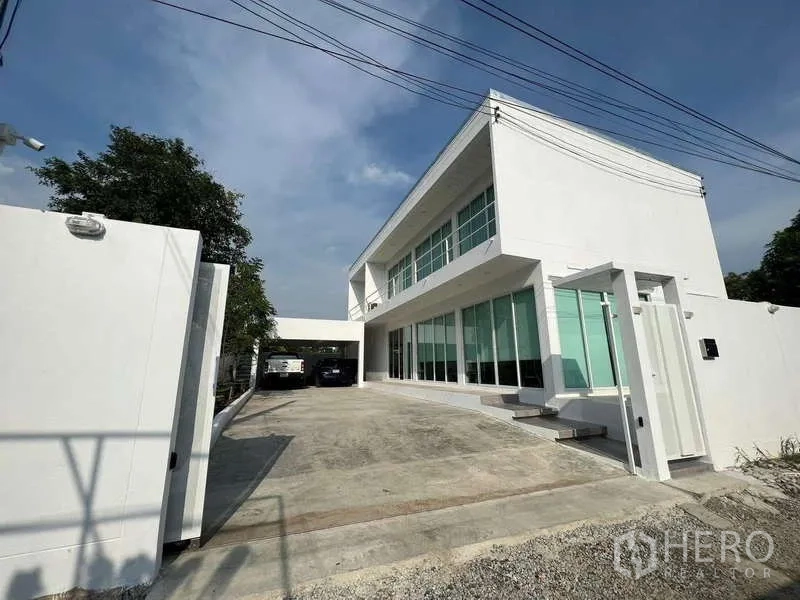 独立式住宅 出租在Lat Krabang, Bangkok - 正面外观：现代白色独栋别墅，宽阔车道与大窗。