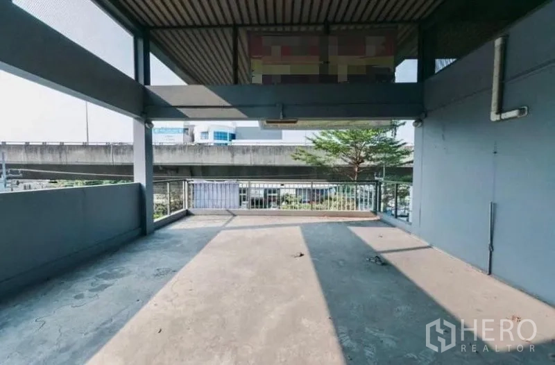 Home Office for rent or sale - Large upper-floor terrace with roof cover and railing, facing an elevated roadway.