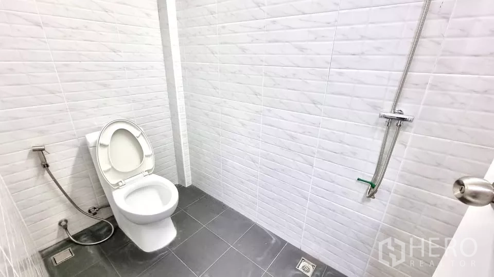 Townhouse for rent in Huai Khwang, Bangkok - White-tiled bathroom with shower and handheld bidet spray.