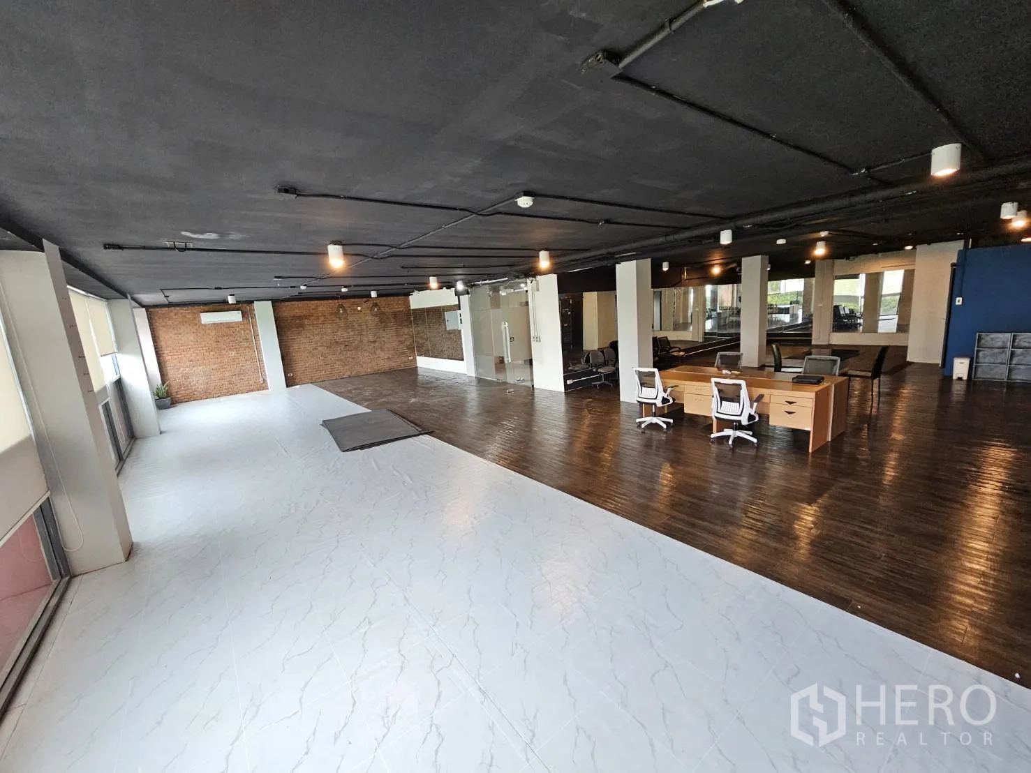 Office Space for rent in Watthana, Bangkok - Bright office area with white-tiled section, brick back wall, desks and long windows with blinds.