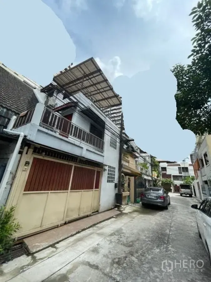 Townhouse for sale in Khlong Toei, Bangkok - Three-storey townhouse exterior with balcony, metal gate, and covered rooftop on a quiet residential lane.