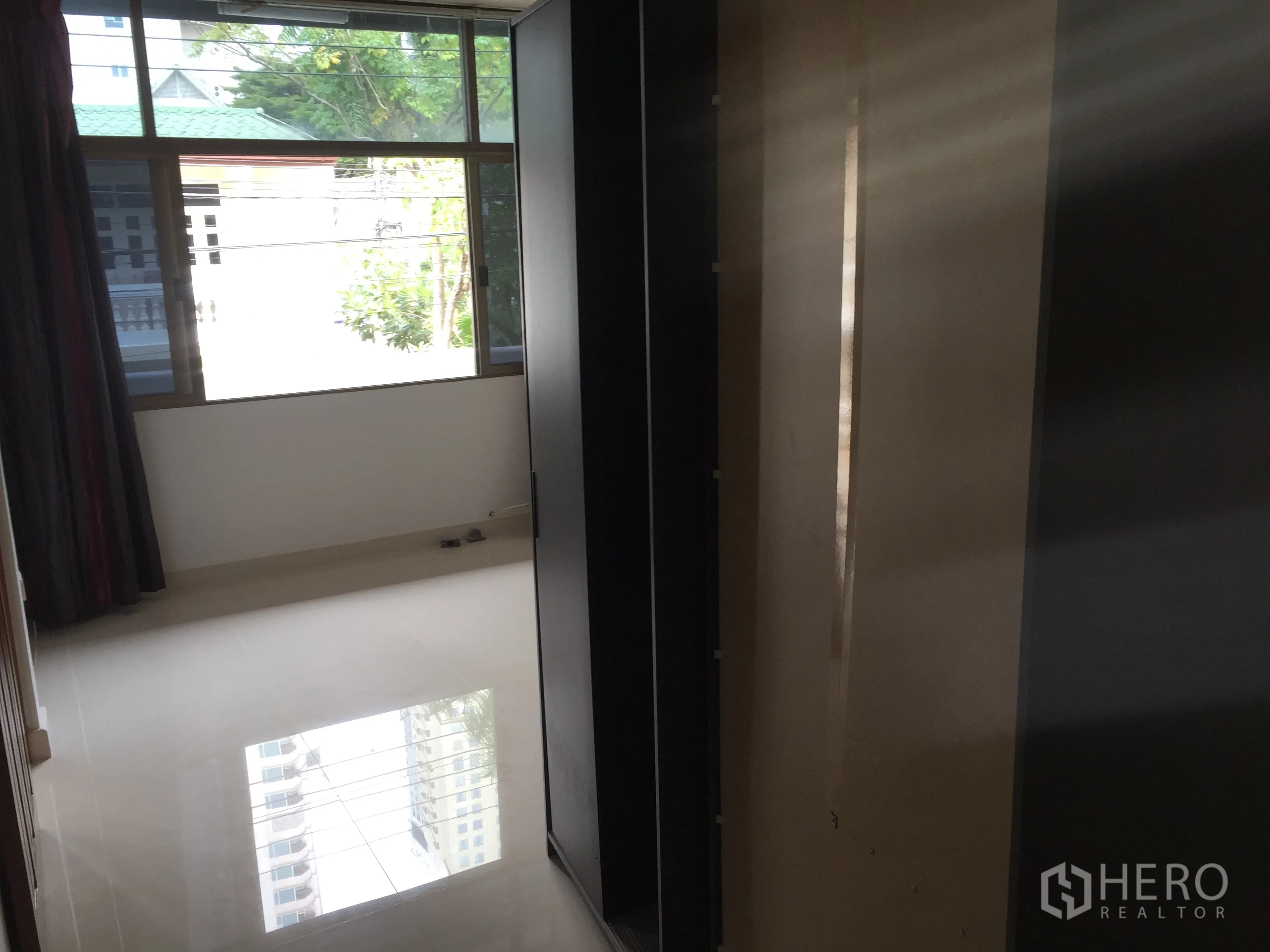 联排别墅 出租在Khlong Toei, Bangkok - 卧室配大窗与亮面地砖，衣柜框架到位，视野有绿意。