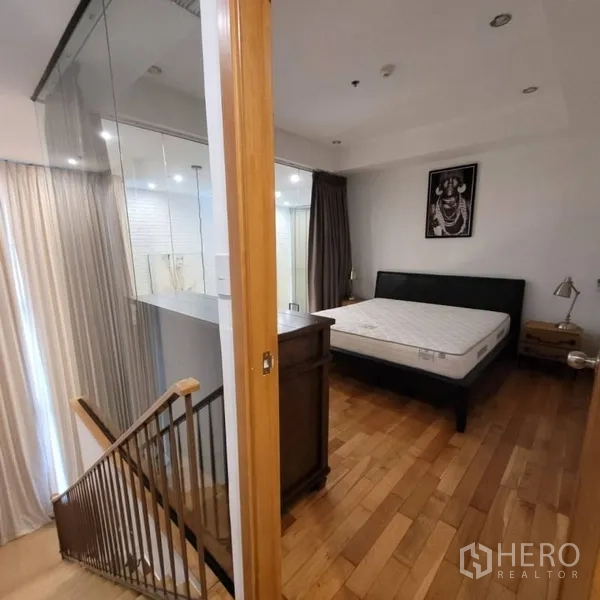 Condominium for rent in Khlong Toei, Bangkok - Bedroom entry by stairs with glass partition and large curtained windows.