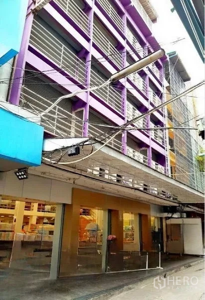 Shophouse for rent in Pathum Wan, Bangkok - Exterior of a multi-storey purple shophouse with wide glass storefront and metal louvers in Pathum Wan, Bangkok.