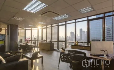 Office Space for rent in Khlong Toei, Bangkok - Bright open-plan office with floor-to-ceiling windows, sunset city skyline views, wood floors, desks and ceiling AC.