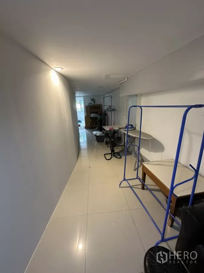Retail Space for rent - Long tiled passage with blue racks and tables inside a compact retail space.