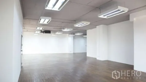 办公空间 出租 - 长条形开放办公区，木地板与条形照明，简洁白墙。