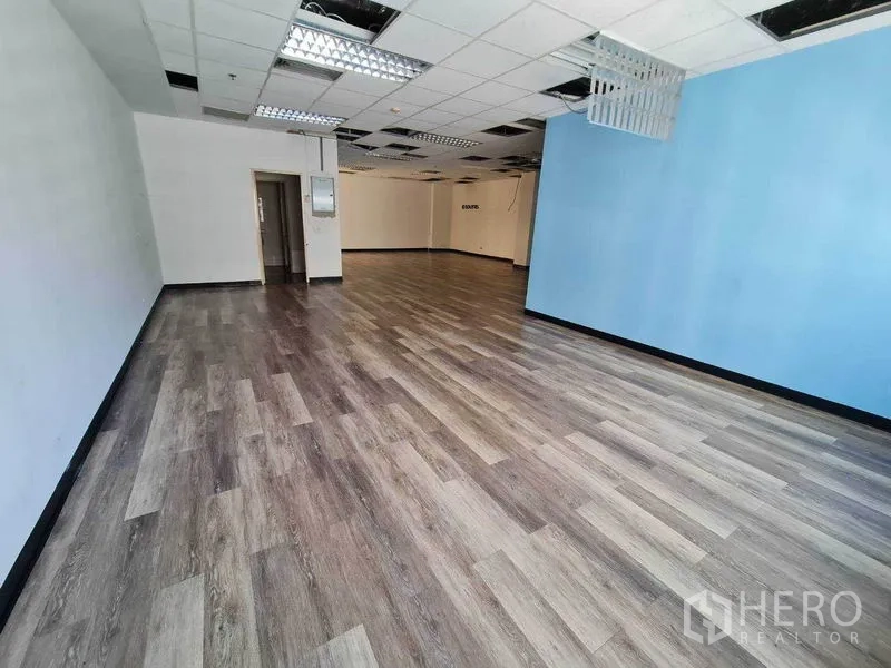 Office Space for rent in Watthana, Bangkok - Long open office with blue accent wall, suspended ceiling and wood floors.