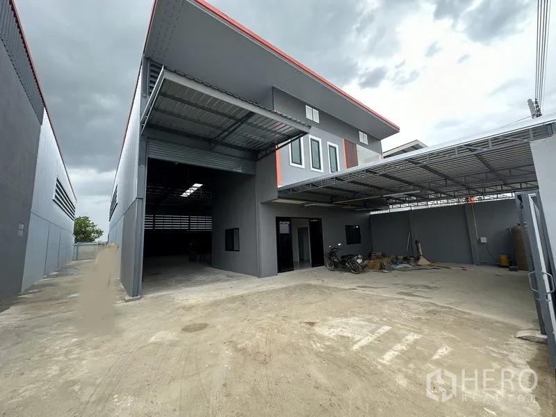 Warehouse for rent in Lam Luk Ka, Pathum Thani - Wide driveway and covered loading bay with roller shutter and office windows at the front yard.