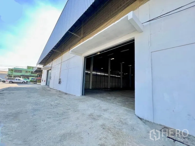 Warehouse for rent in Pak Kret, Nonthaburi - Warehouse exterior showing wide roll-up door, concrete loading apron and driveway with easy street access.