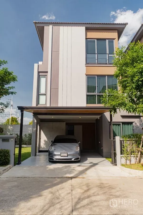 Detached House for rent or sale in Prawet, Bangkok - Modern three-storey house facade with covered carport, driveway and corner lawn