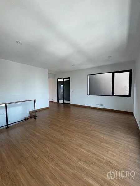 Townhouse for rent - Large multipurpose room with wood floors and black-framed glass door.