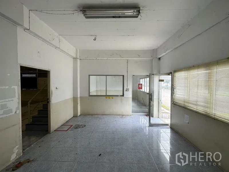 Factory for rent in Phra Nakhon Si Ayutthaya - Ground-floor office or reception with tiled floor, large window and glass entrance door.