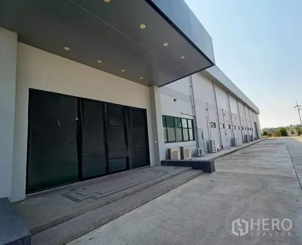 Warehouse for rent or sale in Pathum Thani - Shaded loading entrance and side elevation of the warehouse with ample parking apron.