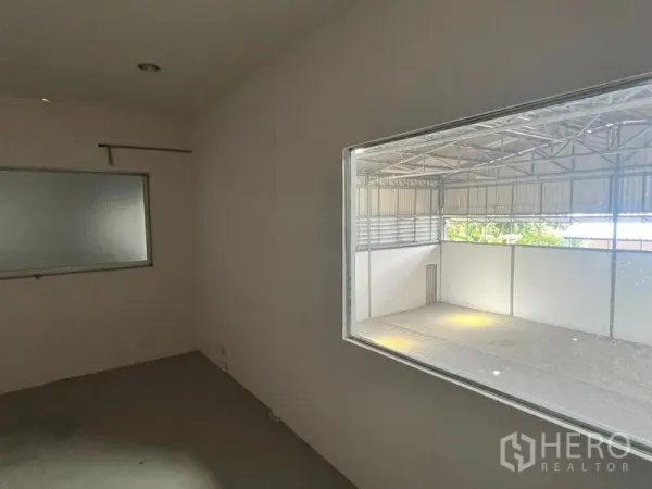 Warehouse for rent in Suan Luang, Bangkok - Compact office room with internal window overlooking a high-ceiling warehouse floor.
