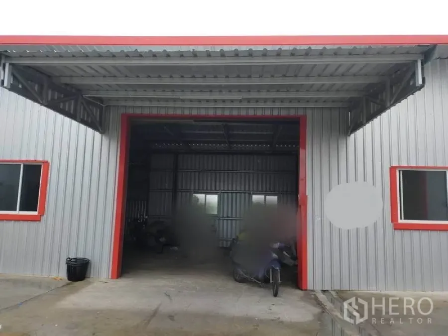 Warehouse for rent in Bang Yai, Nonthaburi - Metal-clad warehouse facade with wide covered loading bay, red trim and windows.