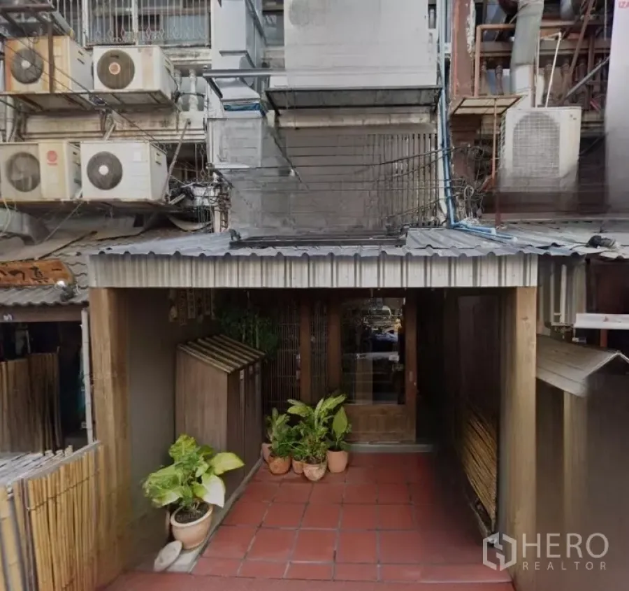 Shophouse for rent in Bang Rak, Bangkok - Bang Rak shophouse exterior with metal awning, tiled entry and potted plants.