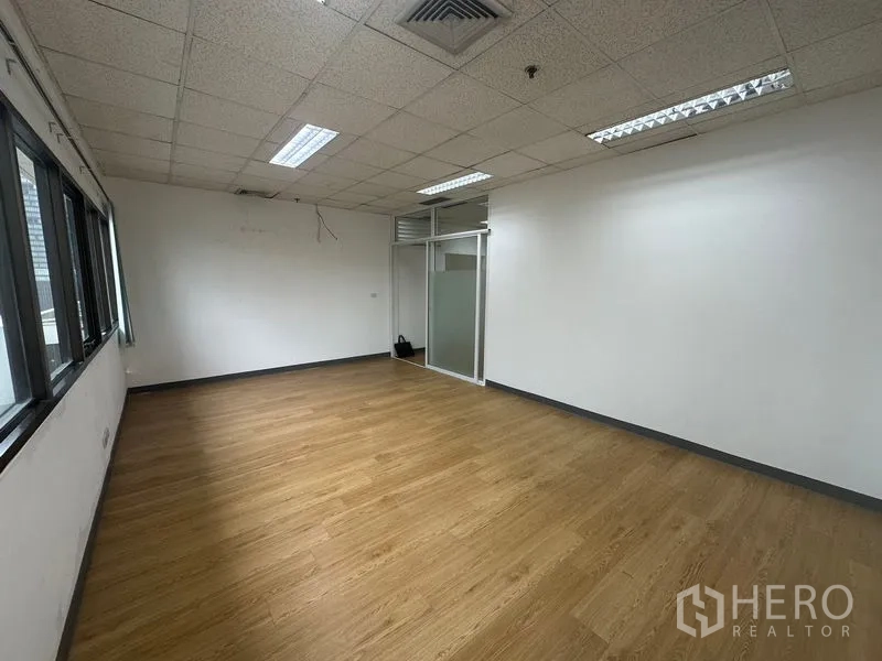Office Space for rent in Watthana, Bangkok - Large open-plan area with frosted-glass entry and laminate wood flooring.