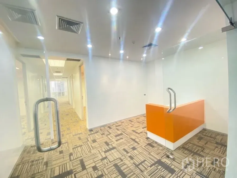 Office Space for rent in Chatuchak, Bangkok - Reception area behind glass doors with orange front desk and recessed lighting.
