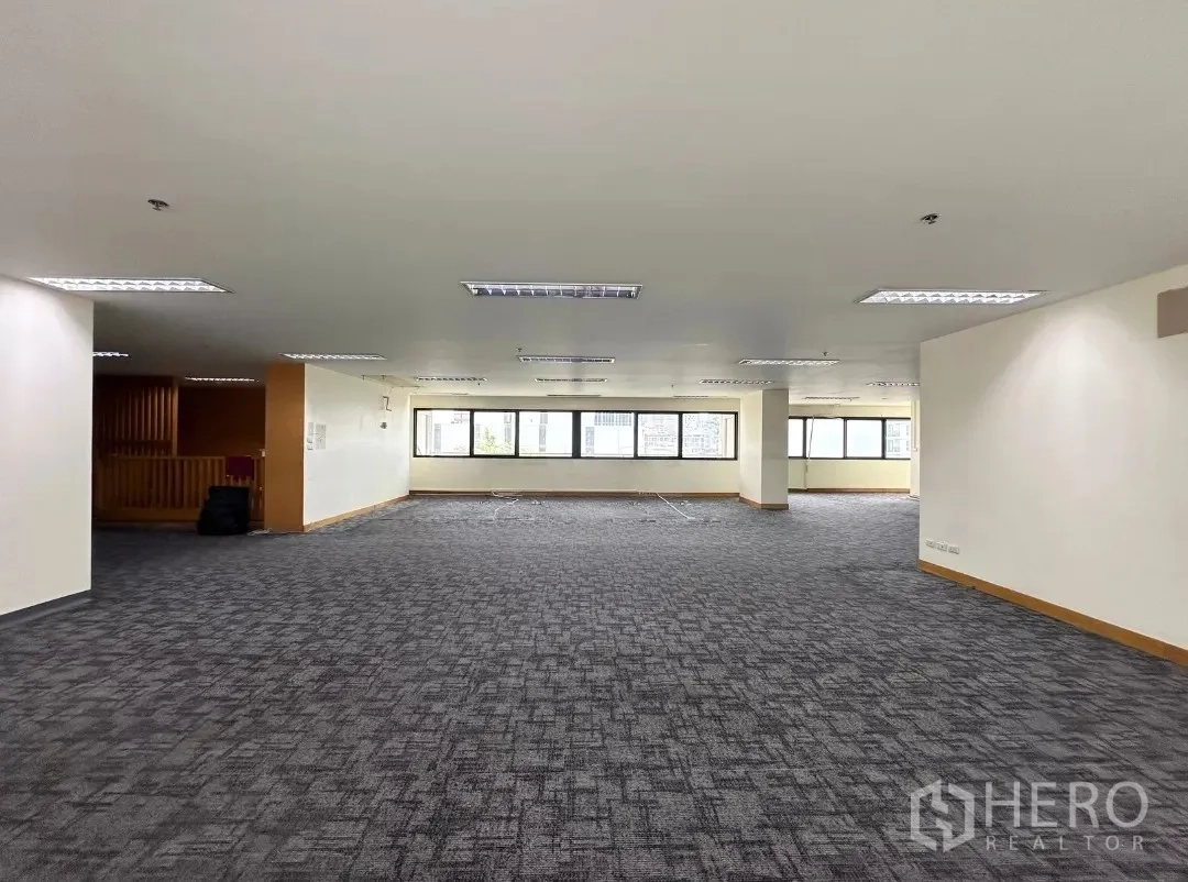 Office Space for rent in Bang Rak, Bangkok - Large open workspace with long window line and ceiling fluorescent lights.