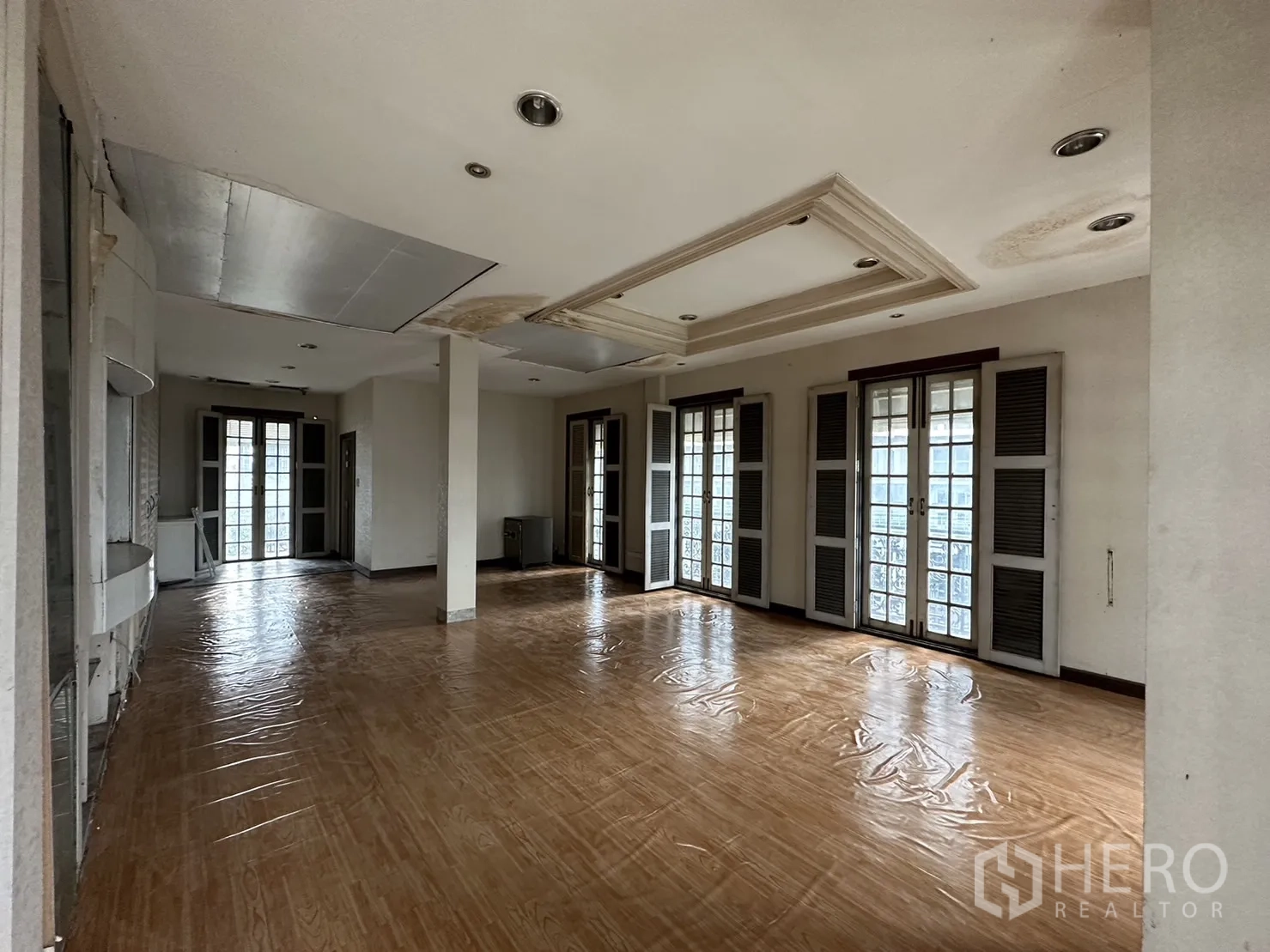 Home Office for rent in Huai Khwang, Bangkok - Spacious open-plan room with multiple French doors and wood-look flooring.