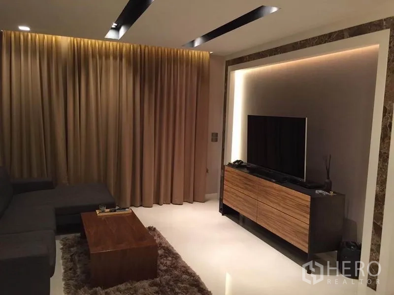 Detached House for rent or sale in Khlong Toei, Bangkok - TV feature wall with wood media console, cove lighting and marble trim facing the sofa.
