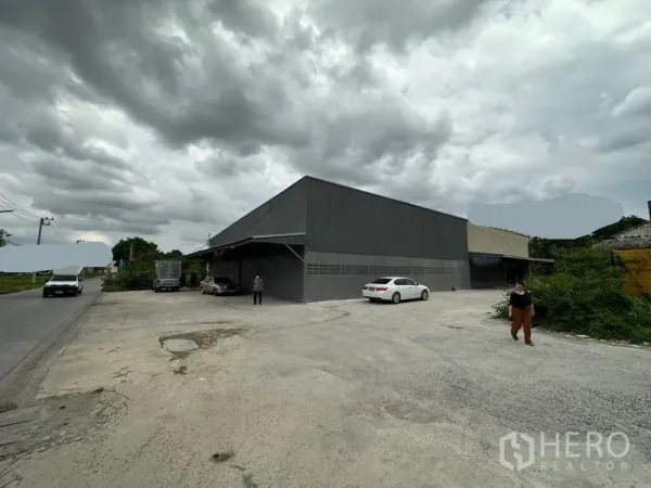 Warehouse for rent in Thanyaburi, Pathum Thani - Corner perspective of the warehouse with expansive driveway and road frontage suitable for truck access.