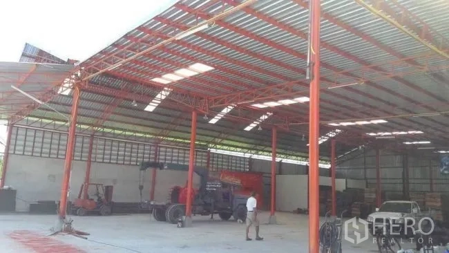 工厂 出售在Phanat Nikhom, Chon Buri - 钢结构厂房内部，红色立柱与叉车及设备，空间宽敞。