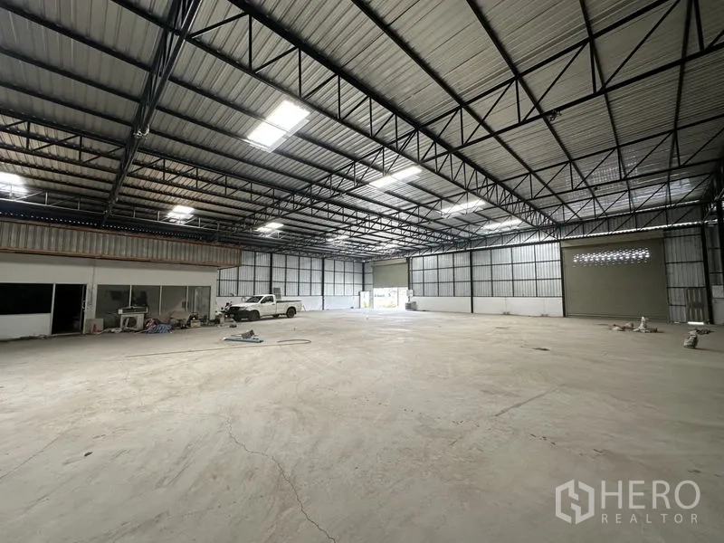 Warehouse for rent in Khlong Luang, Pathum Thani - Warehouse bay showing twin roller shutter doors, smooth concrete floor and high clear-span roof.