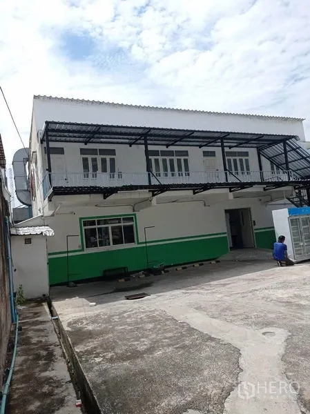Warehouse for rent in Sathon, Bangkok - Two-storey warehouse exterior with metal awning, balcony walkway, and wide loading yard.